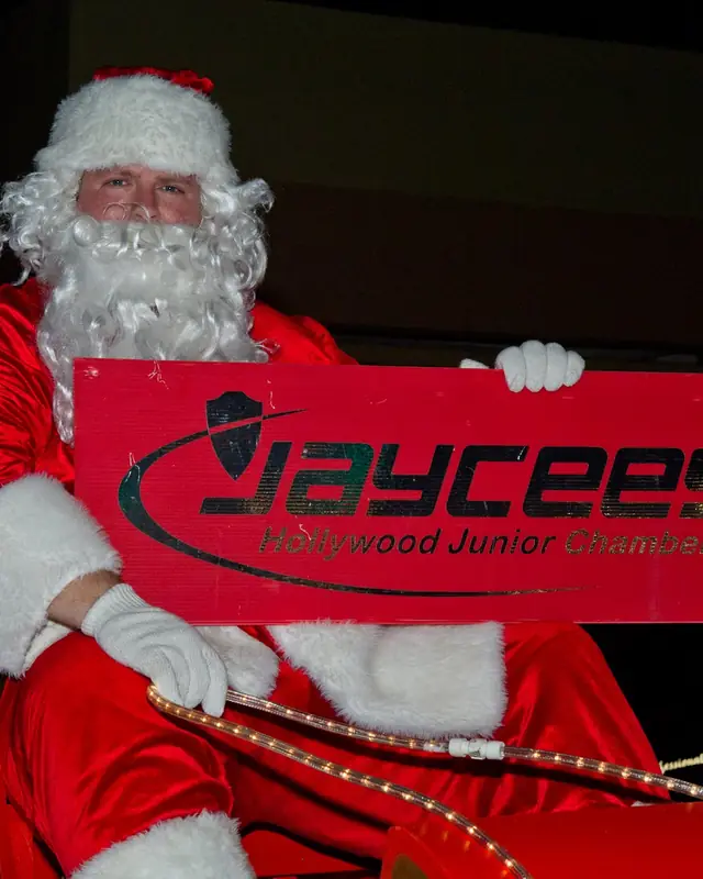 Santa on the Jaycees float at night, holding a red Jaycees sign