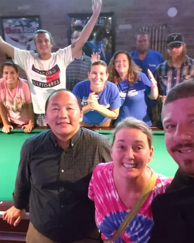 Members cheering around a pool table
