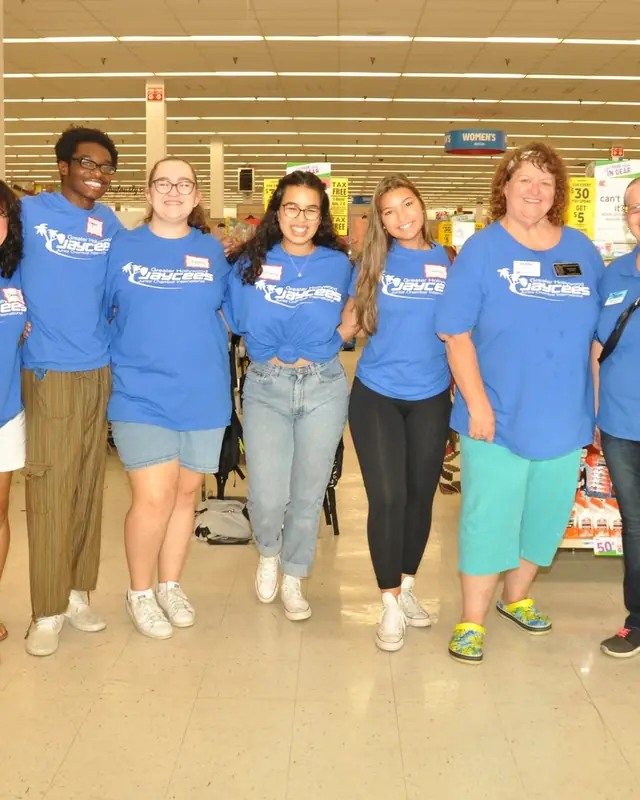 Seven members in matching blue Jaycees shirts in a store