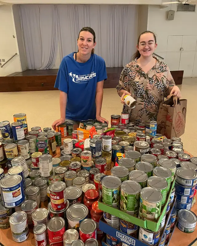 Two members behind a table covered in donated cans